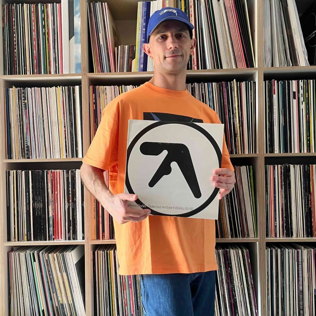 Massimiliano Pagliara vor seinem Plattenschrank mit einem Album von Aphex Twin.