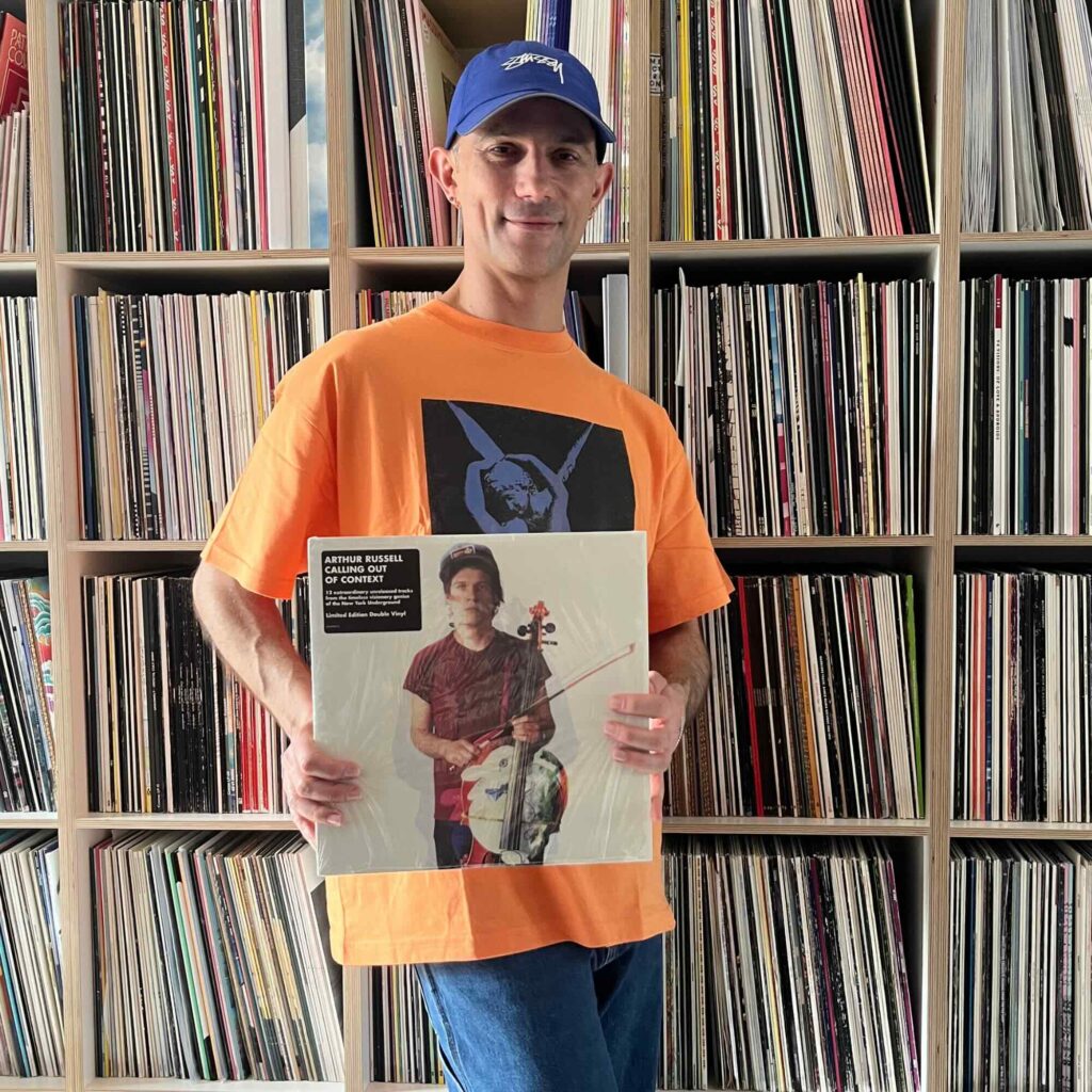 Massimiliano Pagliara mit einem Album von Arthur Russell vor seinem Plattenschrank.