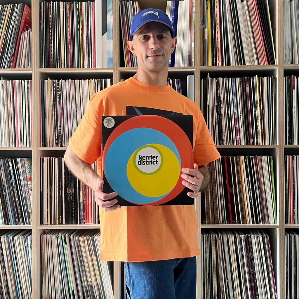 Massimiliano Pagliara vor seinem Plattenschrank mit einem Album von Luke Vibert.