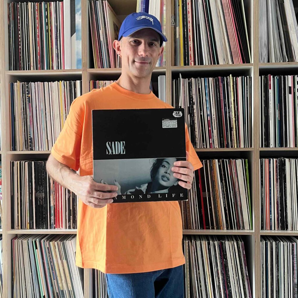Massimiliano Pagliara vor seinem Plattenschrank mit dem Album von Sade.