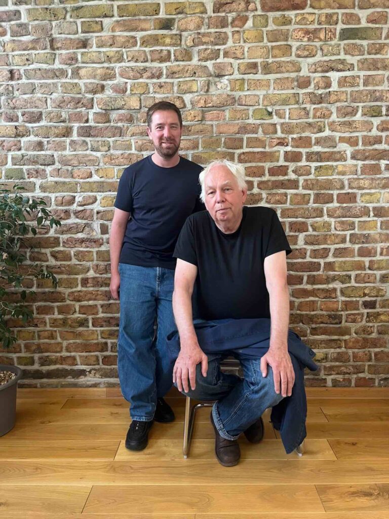 Marcel Weber und Dimitri Hegemann vor einer Ziegelwand.