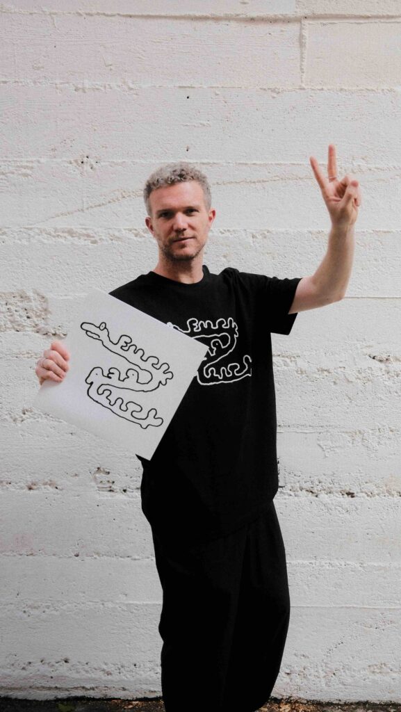 Traumer alias Roman Poncet zeigt das Peace-Zeichen und hält eine seiner Platten in der Hand.